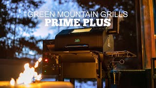 Green Mountain Grills Prime Plus pellet grill in outdoor setting with fire in foreground, showcasing advanced grilling features and evening ambiance.