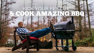 Man relaxing in a chair with feet up, next to a Green Mountain Grill, promoting easy BBQ cooking.