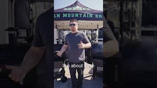Man standing in front of a Green Mountain Grills tent, discussing features of pellet grills for BBQ enthusiasts.