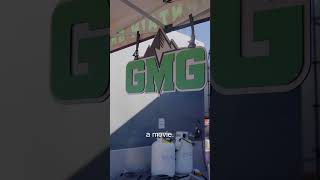 Green Mountain Grills logo in a grilling setup with propane tanks, showcasing the brand's focus on pellet grilling and barbecue.