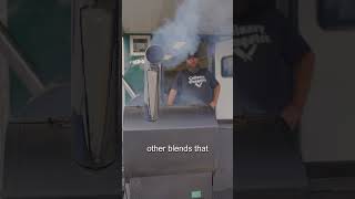 Man standing beside a pellet grill with smoke rising, demonstrating grilling techniques related to BBQ and pellet grilling.