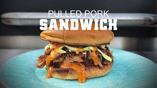 Pulled pork sandwich with coleslaw and sauce on a blue plate, showcasing delicious BBQ food relevant to Green Mountain Grills recipes.