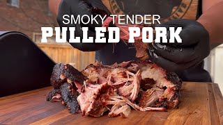 Smoky tender pulled pork on a wooden cutting board, showcasing the texture and juiciness, with a person wearing gloves preparing the meat, highlighting BBQ techniques and Green Mountain Grills usage.